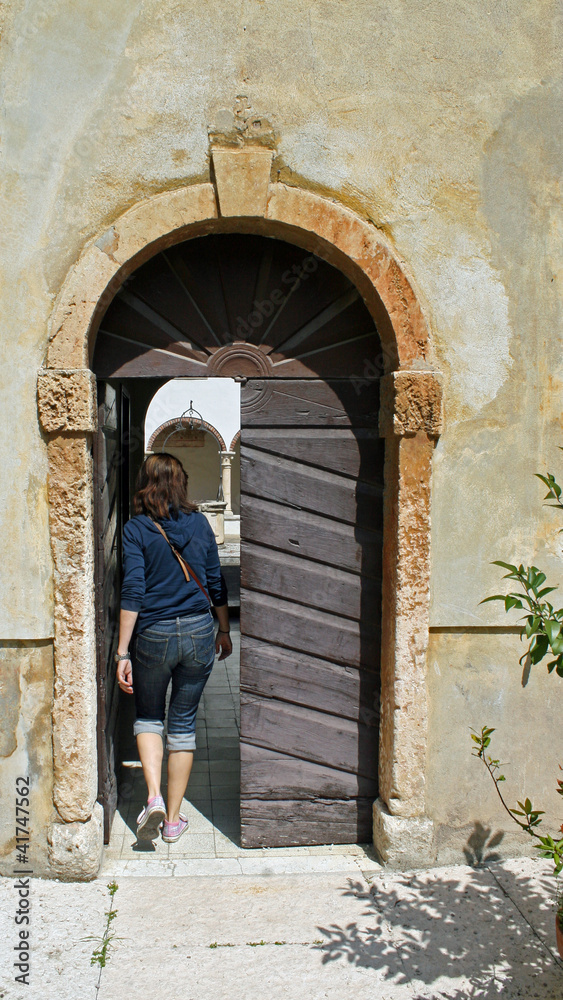 Woman who enters into a door of an old convent