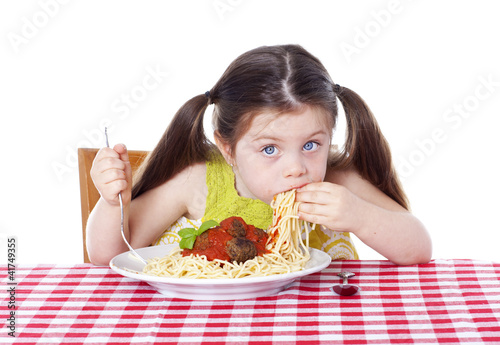Beautiful girl eating pasta and meatballs with hands