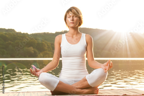 Young woman meditating on the lake