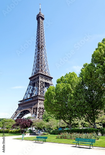 Tour Eiffel, jardin avec bancs, ciel bleu.