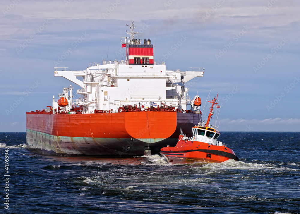 Tugboat towing a large cargo ship in port. Tugboat towing a large cargo ship in port.