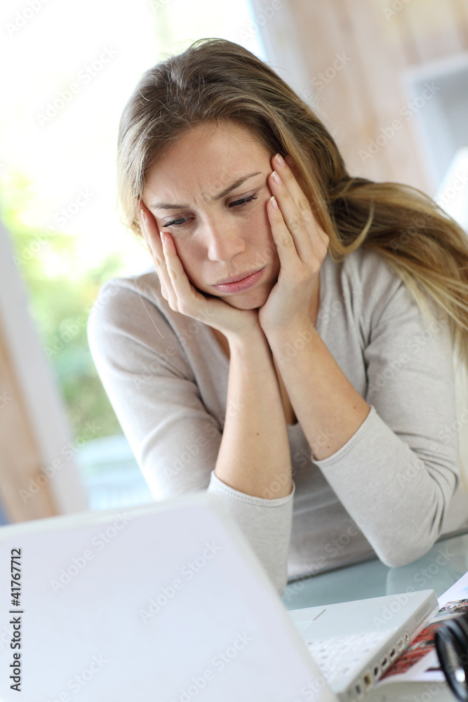 Active woman in front of laptop with upset look Active woman in front of laptop with upset look