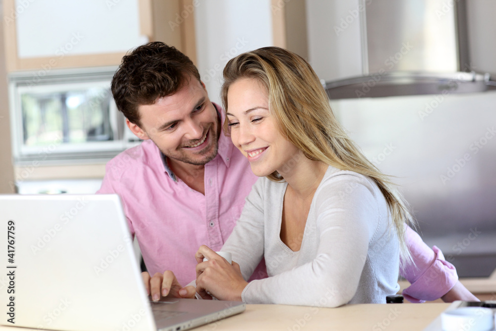 Happy couple websurfing on laptop computer at home Happy couple websurfing on laptop computer at home