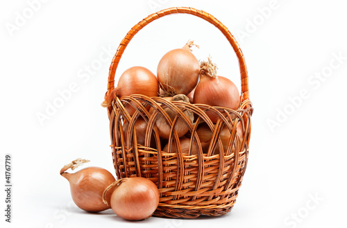 Fresh bulbs of onion in basket on a white background