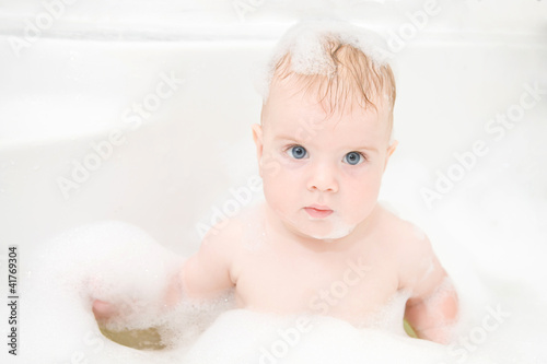 baby boy with blond hair and blue eyes is washing