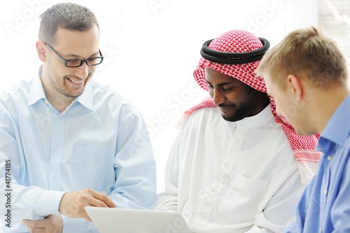 Multicultural different ethnic group working on laptop together photo
