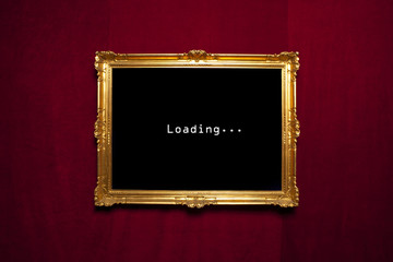 Antique gold frame with a loading sign on a red velvet wall