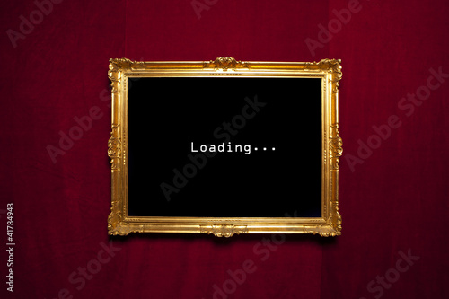 Antique gold frame with a loading sign on a red velvet wall