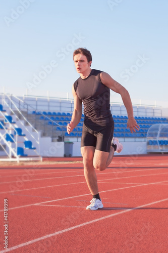 A young man starts running in the stadium. Treadmill.