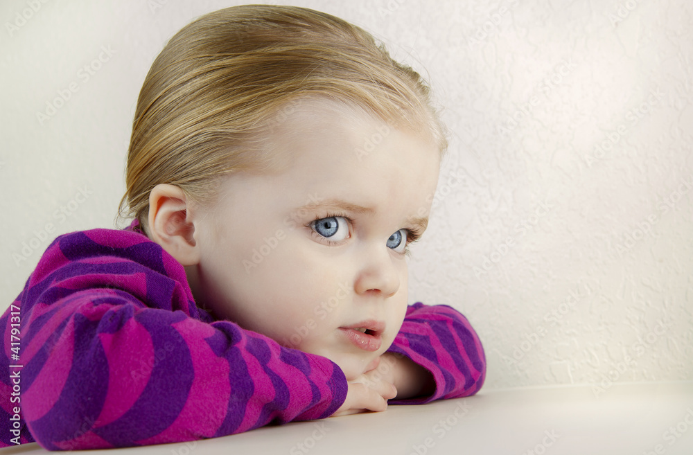 Cute young girl resting her head on a table. Cute young girl resting her head on a table.