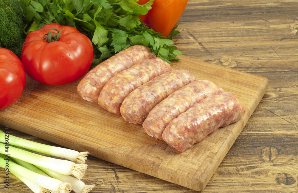 Raw sausages and fresh vegetables closeup. Raw sausages and fresh vegetables closeup.
