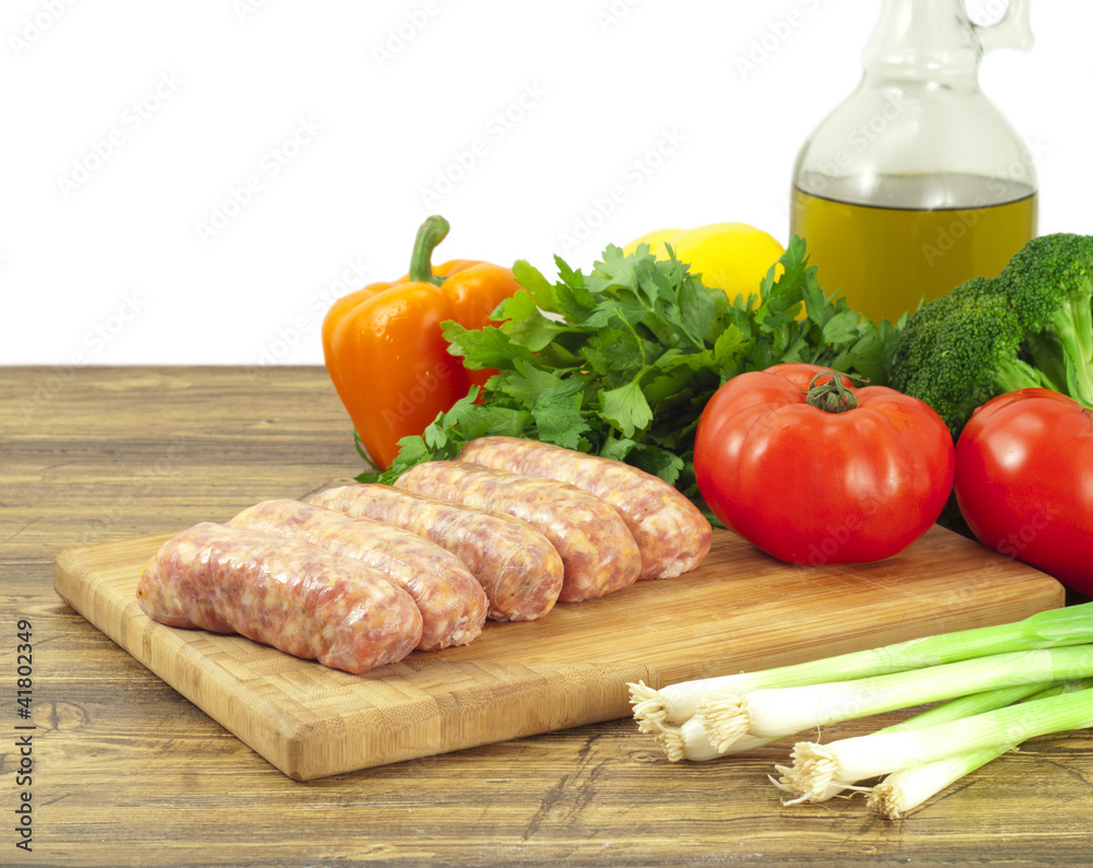 Raw sausages and fresh vegetables on a cutting board Raw sausages and fresh vegetables on a cutting board