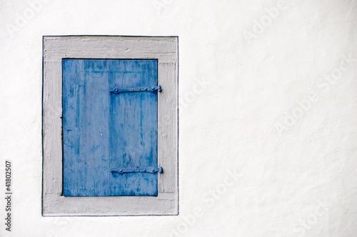 Blauer Fensterladen auf weißer Wand