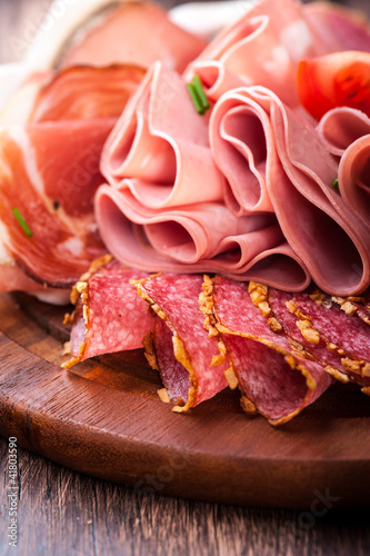 Fotografía Sliced cold cuts on wooden chopping board