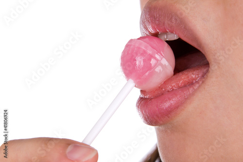 Woman licking a pink shiny lollipop on white background.