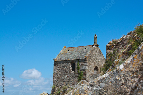 Stone chapel with a saint on the roof
