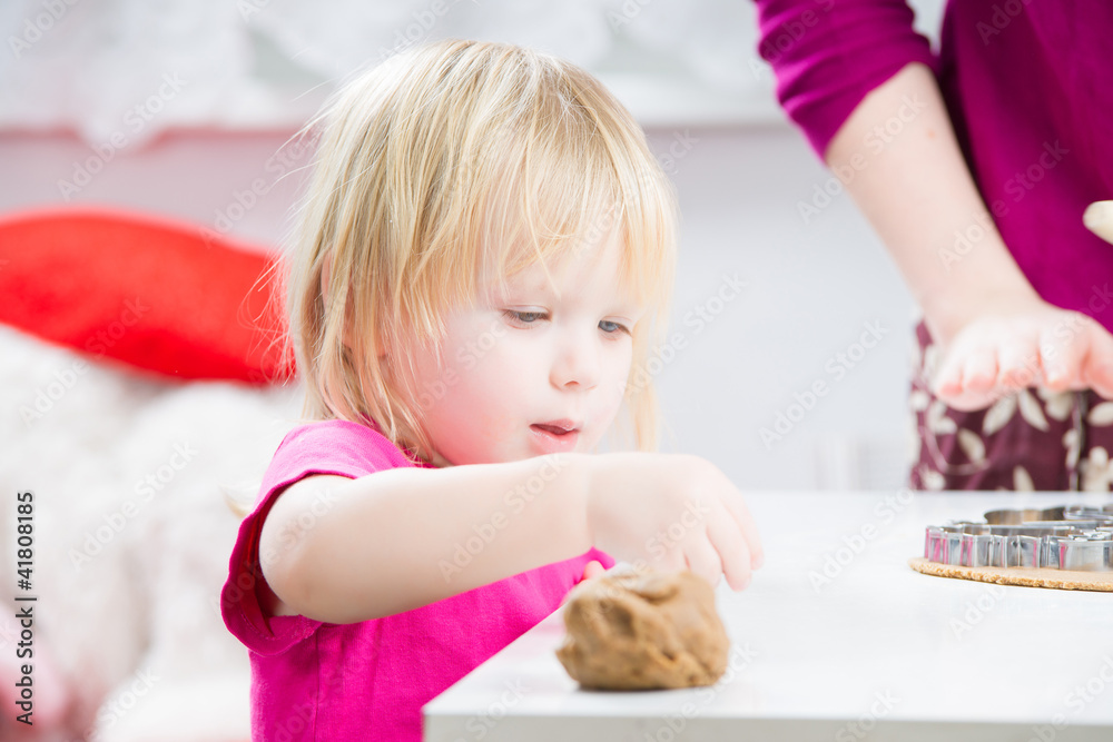 Baby helps mother with baking gingerbread cookies in kitchen Baby helps mother with baking gingerbread cookies in kitchen