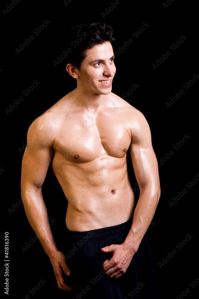 Smiling fit man flexing his muscles on black background
