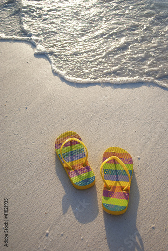 A PAIR OF COLOURFUL FLIP FLOPS AT THE WATER’S EDGE
