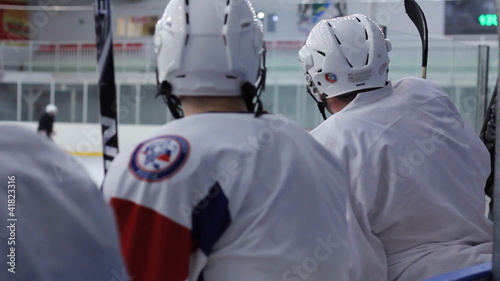 Hockey players are sitting on the bench with his back
