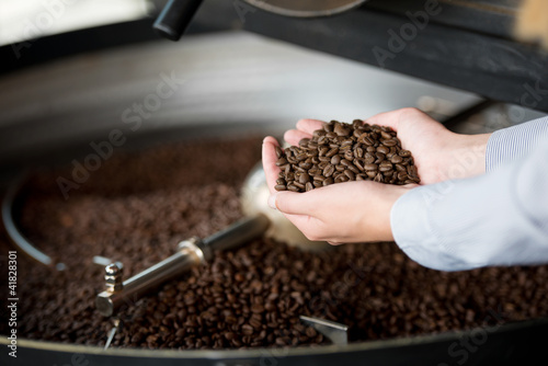 frau in der rösterei hält kaffeebohnen in der hand