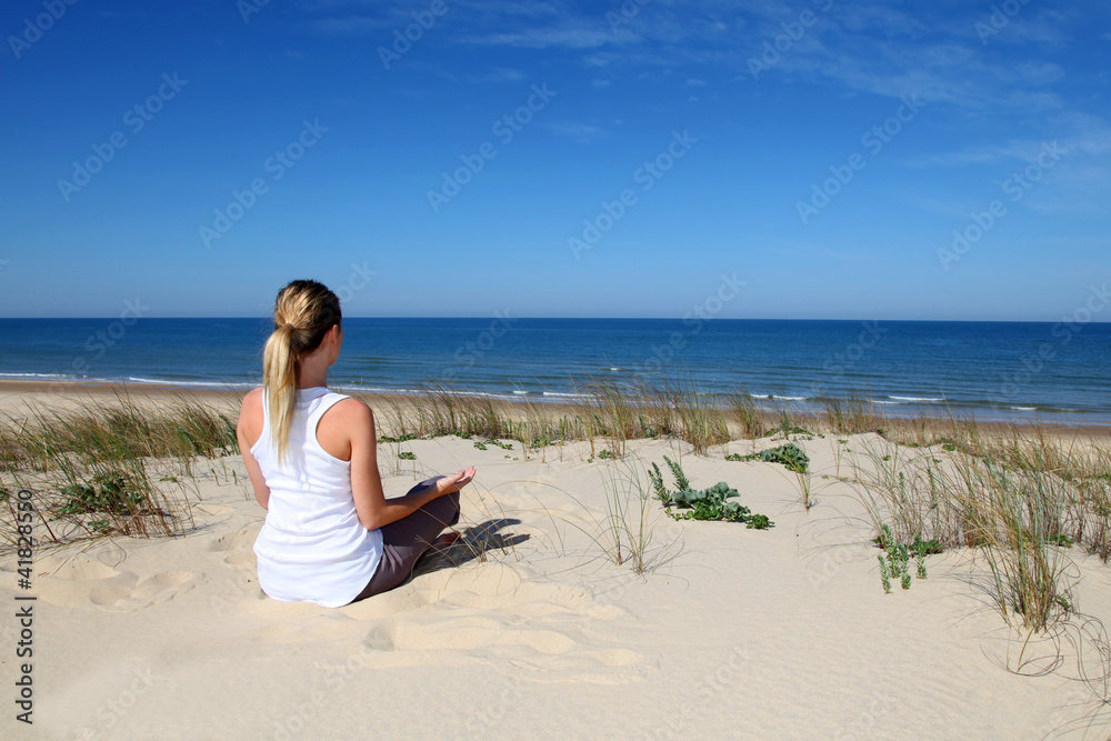 Woman practicing yoga on the beach