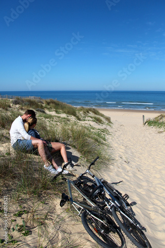 Couple sitting by bicycles on a sand dune