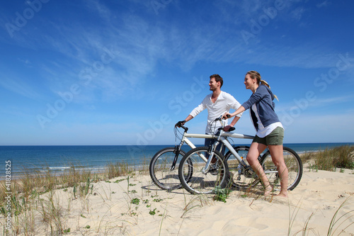Couple standing on a sand dune with bicycles