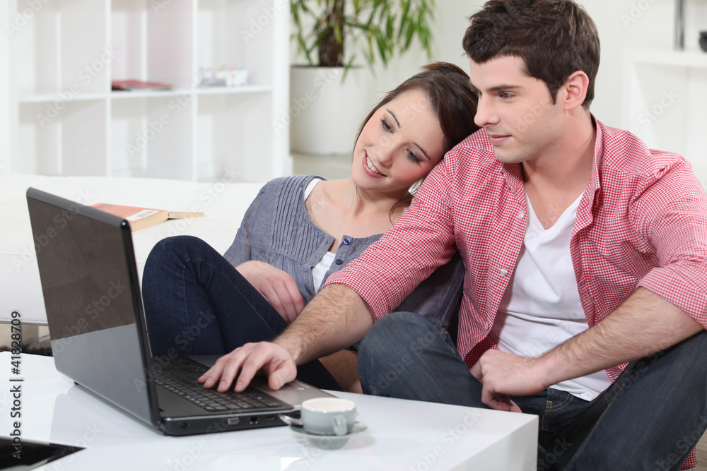 Couple relaxing at home in front of their laptop