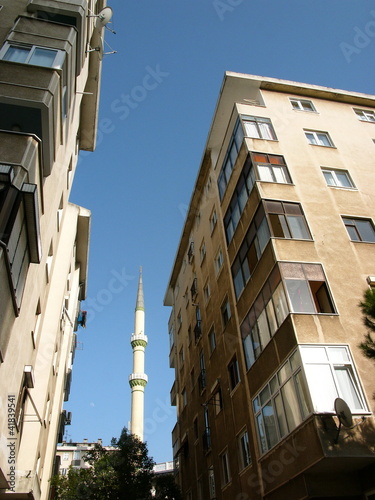 Photography Hochhäuser mit Wohnungen und Minarett einer Moschee vor blauem Himmel im Sonnens