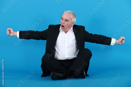 businessman sitting cross-legged and stretching