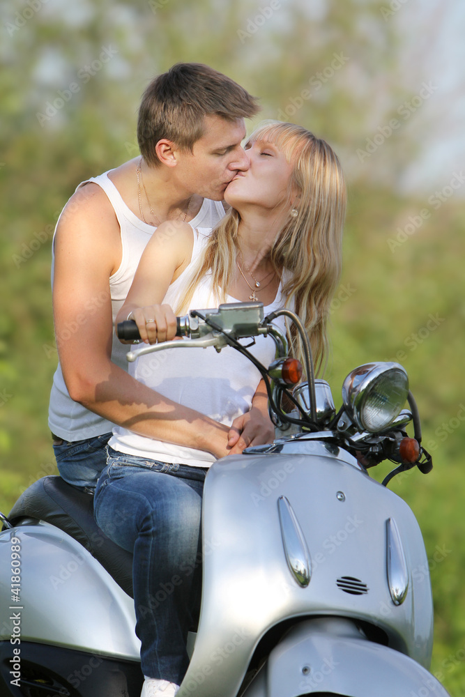 young loving couple on motorbike / scooter on natural background