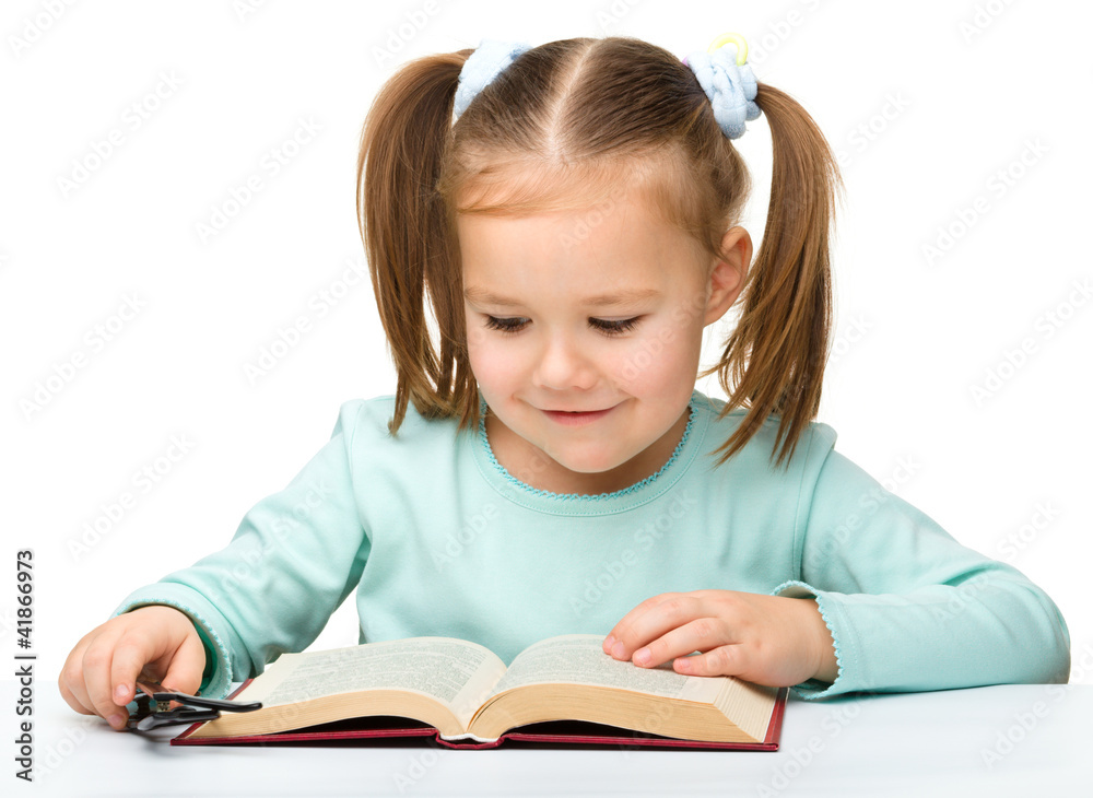 Little girl reads a book while wearing glasses Little girl reads a book while wearing glasses