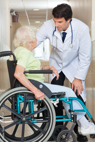 Doctor Communicating With Senior Woman Sitting In Wheelchair