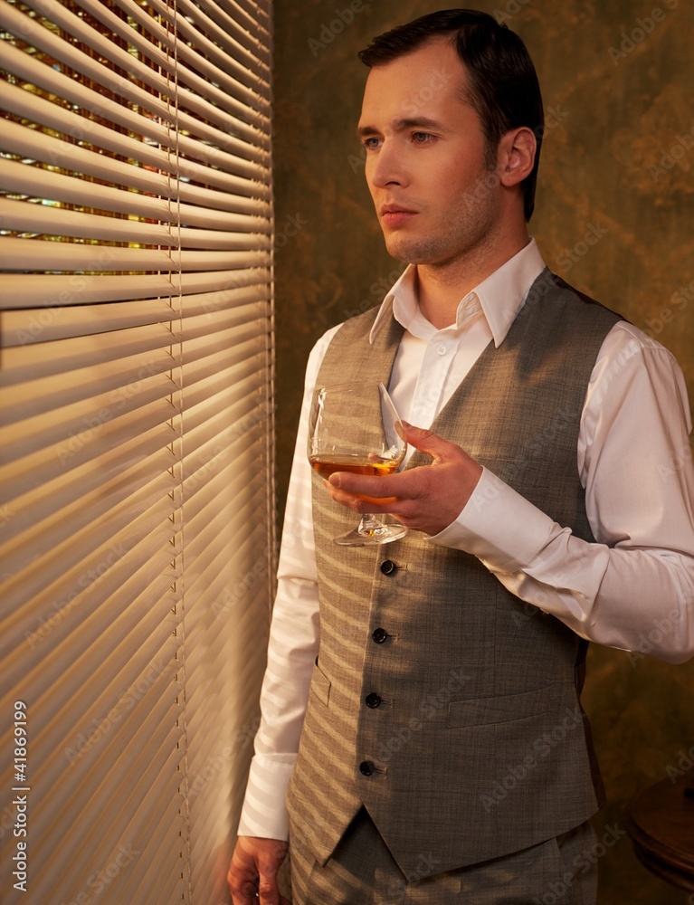 Fototapeta premium Man with a glass near a window.