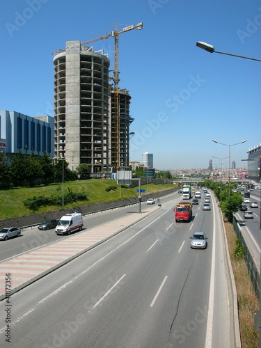 Mehrspurige Schnellstraße mit Hochhaus Neubauten und Baukran vor blauem Himmel im Sonnenschein im Stadtteil Erenköy in Sahrayicedit in Istanbul am Bosporus in der Türkei photo