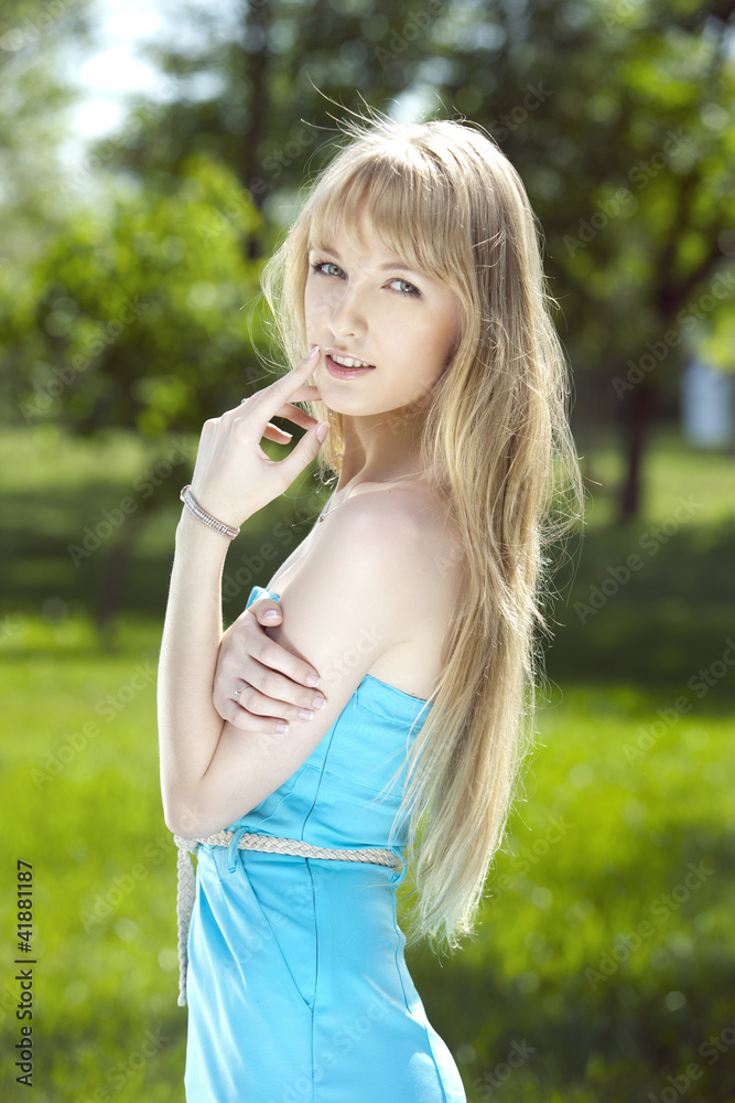 Coquettish girl with long blond hair in a blue dress