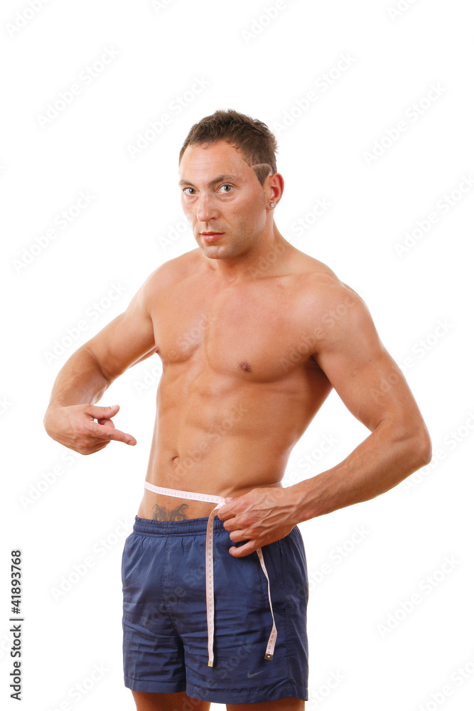 A muscular man measuring his waist