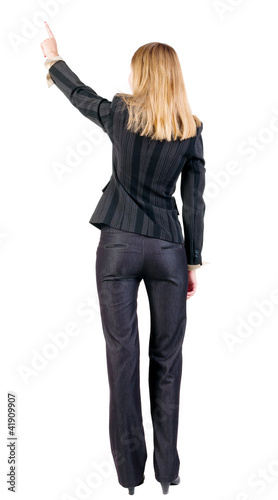 Back view of young blonde business woman pointing at wall .