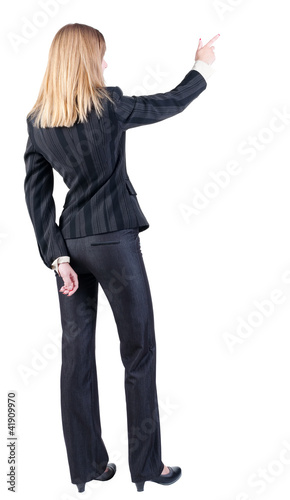 Back view of young blonde business woman pointing at wal
