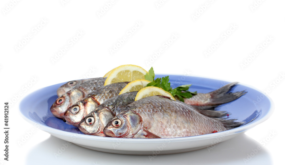 Fresh fishes with lemon and parsley on plate isolated on white Fresh fishes with lemon and parsley on plate isolated on white