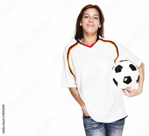 lachende junge frau in fussball trikot mit fußball unter dem arm