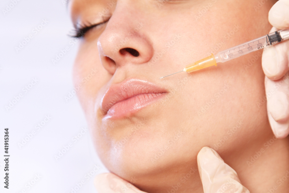 Close-up young woman receives cosmetic injection with syringe