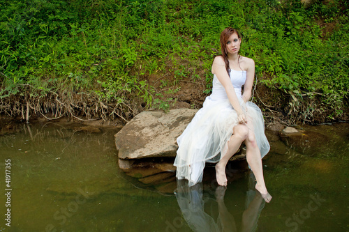 Wet woman sitting on a rock over the water