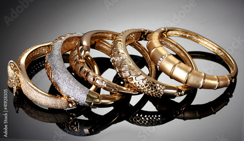 Beautiful golden bracelets on grey background photo