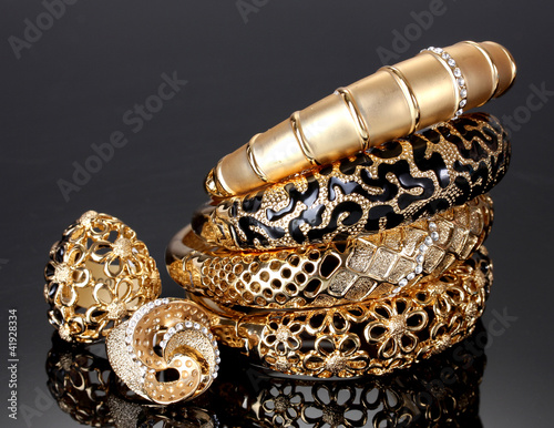 Beautiful golden bracelets and rings on grey background