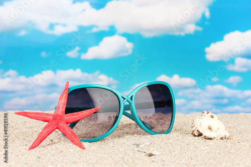 Elegant women's sunglasses with starfish and shell at the beach