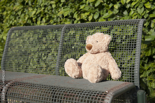 lost teddy bear seated on a iron bench