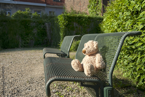 lost teddy bear seated on a iron bench