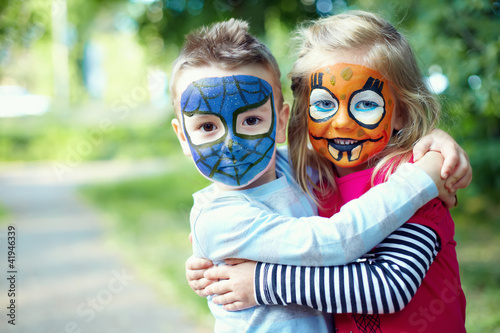 two face painted little friends embracing outside photo